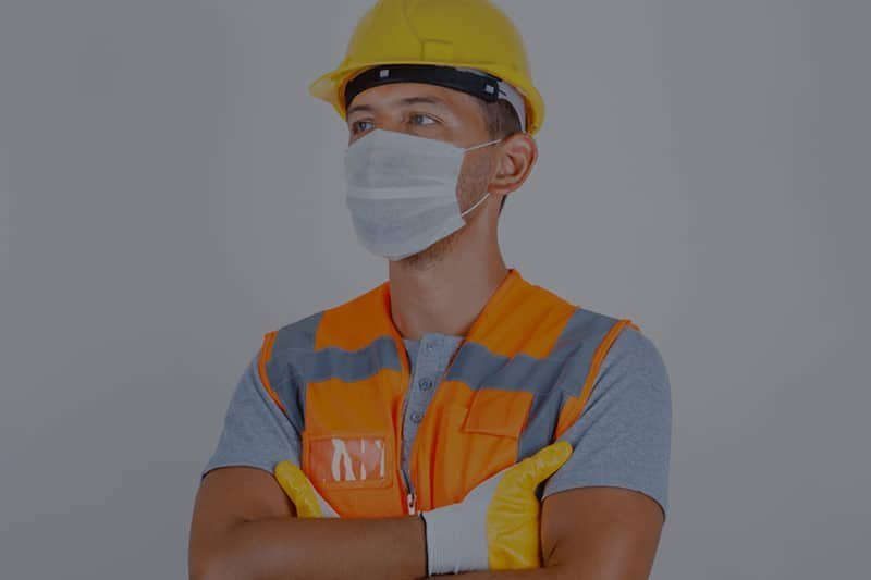 Trabajador con casco, chaleco, mascarilla y guantes de seguridad